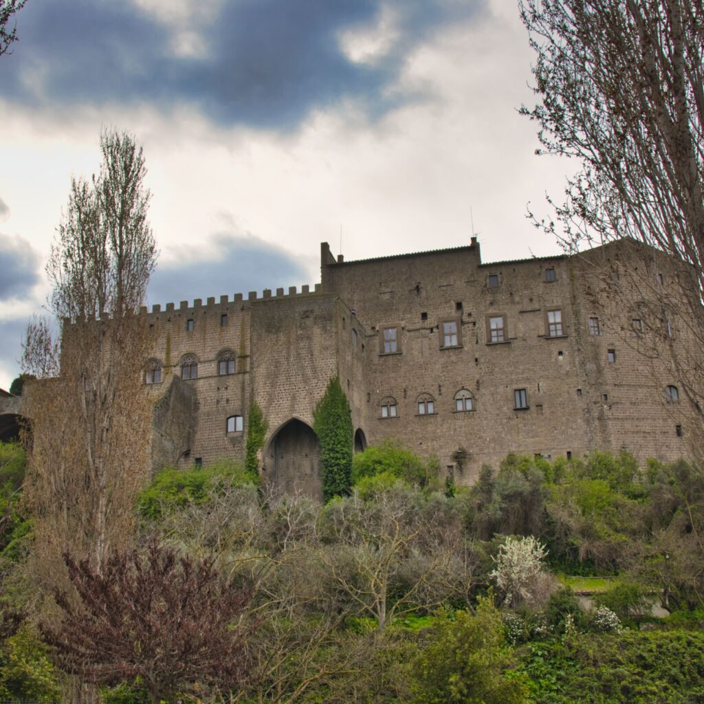 a large stone building with trees and bushes